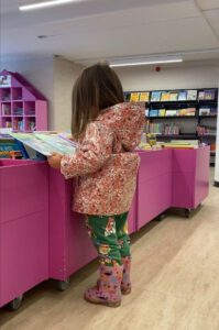 Klein meisje lezend in de bibliotheek